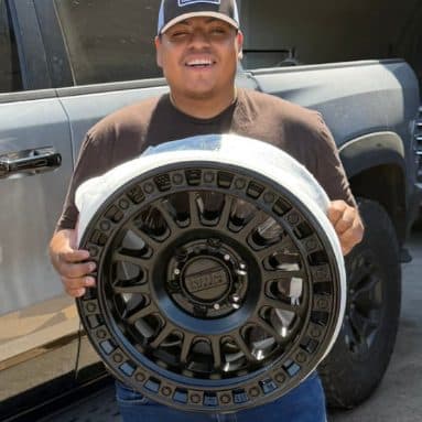 Customer holding a powder-coated black off-road wheel