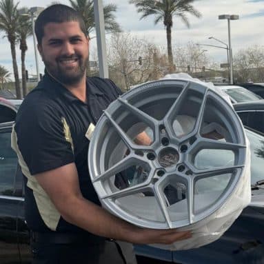 Customer holding a refinished silver multi-spoke wheel
