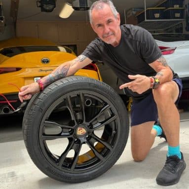 Customer kneeling with a black powder-coated wheel and tire