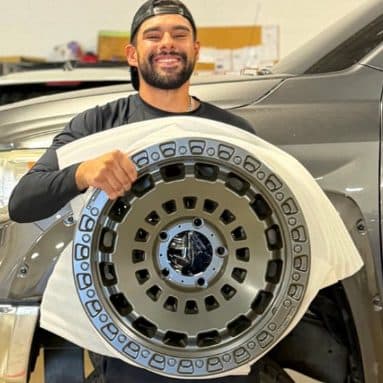 Customer holding a two-tone off-road wheel after powder coating