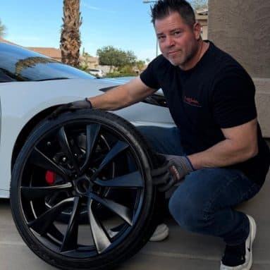 Customer with a gloss black wheel and tire beside a white car
