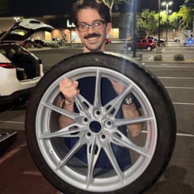 Customer holding a refinished silver wheel and tire