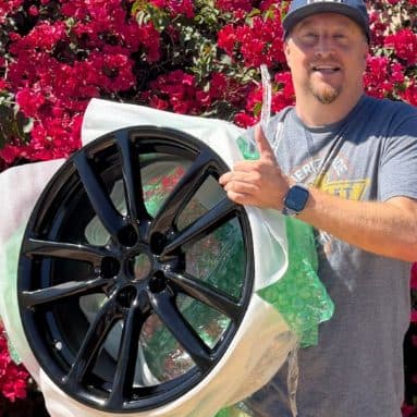 Customer holding a gloss black wheel still in its wrapping