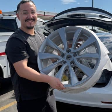 Customer holding a refinished silver multi-spoke wheel