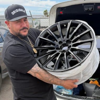Customer holding a black multi-spoke wheel after powder coating