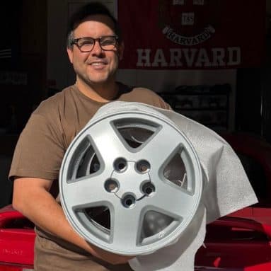 Customer holding a refinished silver five-spoke wheel